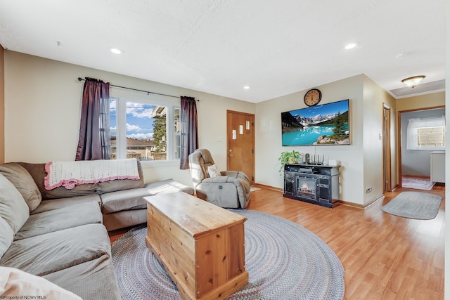 living room featuring a glass covered fireplace, light wood-style flooring, recessed lighting, and baseboards