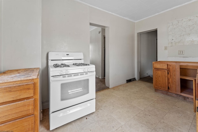 kitchen with white range with gas stovetop, light countertops, brown cabinetry, and ornamental molding