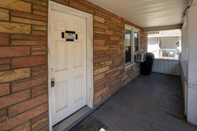 view of exterior entry with covered porch and brick siding