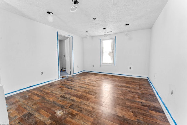 unfurnished room featuring a textured ceiling, baseboards, and hardwood / wood-style floors