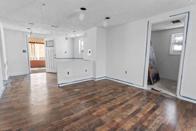 unfurnished living room with visible vents, hardwood / wood-style flooring, baseboards, and a textured ceiling