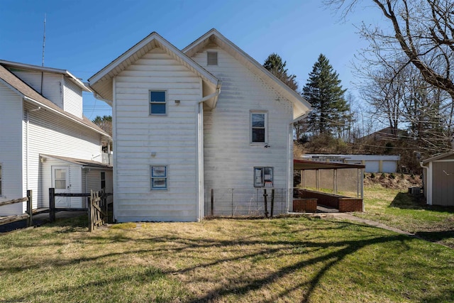 rear view of house featuring an outbuilding, fence, and a yard