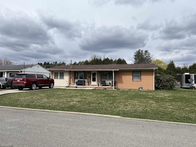 ranch-style home with covered porch, brick siding, driveway, and a front lawn