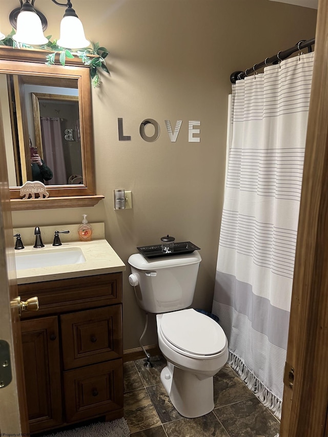 full bath with toilet, vanity, curtained shower, and baseboards