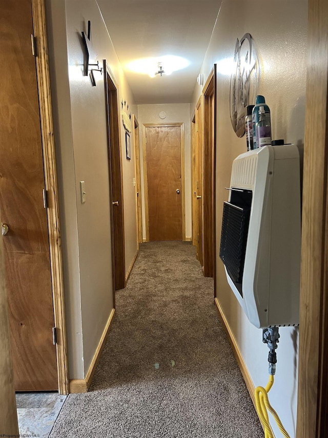 corridor with baseboards, carpet flooring, and heating unit