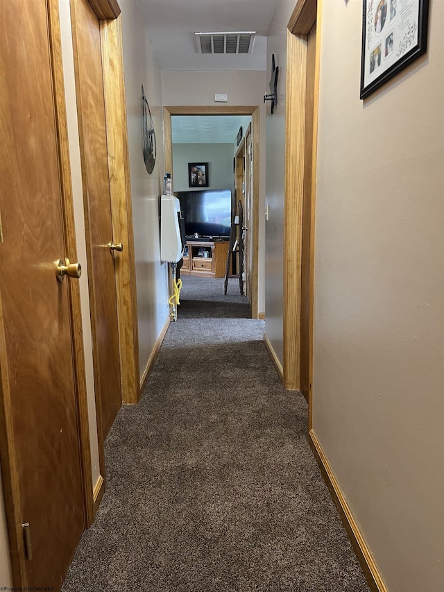 hallway featuring carpet flooring, baseboards, and visible vents