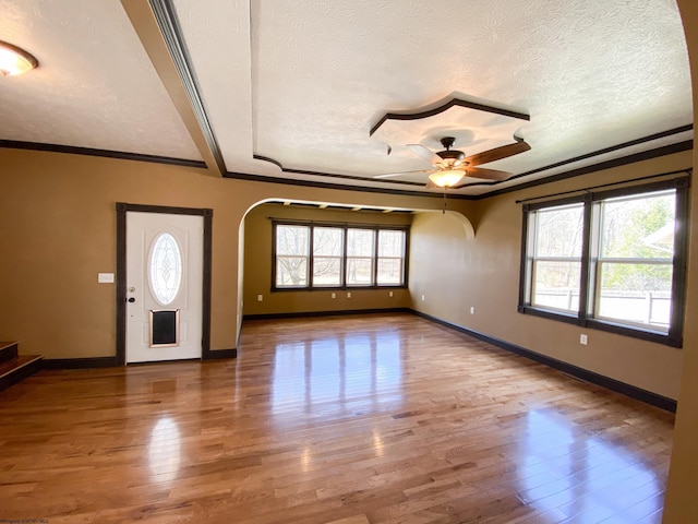 entrance foyer featuring arched walkways, crown molding, a ceiling fan, and hardwood / wood-style flooring
