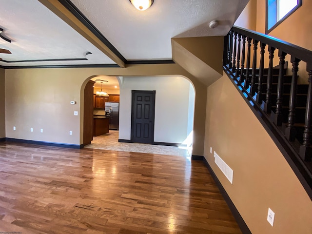 interior space featuring visible vents, light wood finished floors, baseboards, stairs, and arched walkways