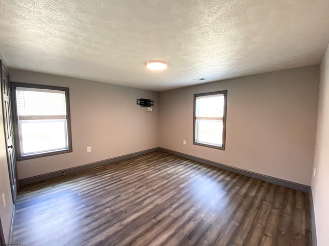 spare room with baseboards, a textured ceiling, and dark wood-style floors