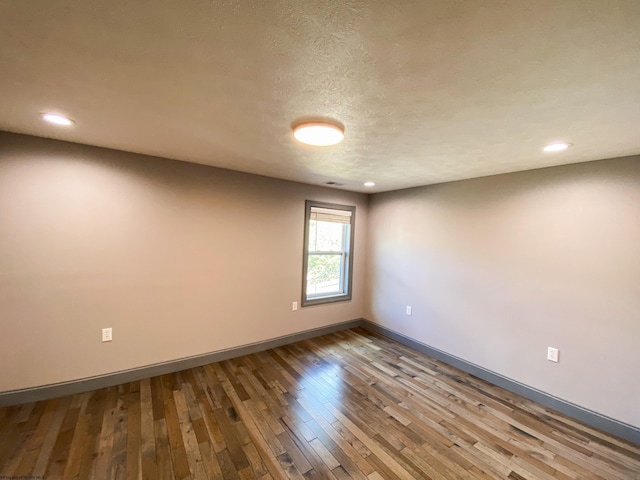 unfurnished room with baseboards, wood finished floors, recessed lighting, and a textured ceiling