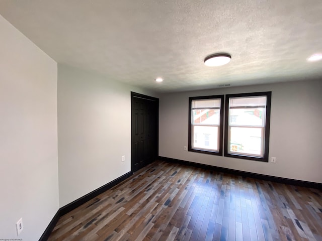 spare room with dark wood-style floors, baseboards, and a textured ceiling