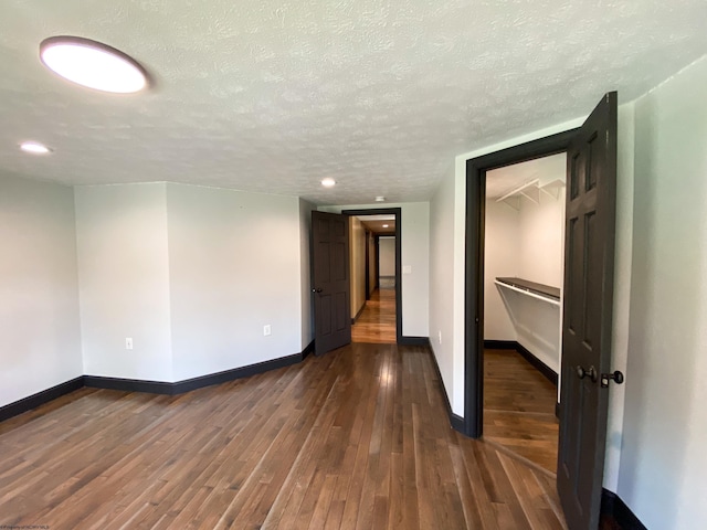 spare room featuring dark wood-style floors, baseboards, and a textured ceiling