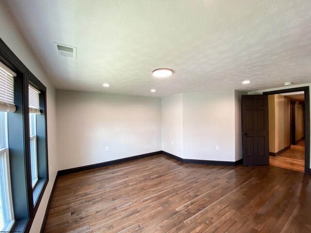 empty room featuring baseboards, a textured ceiling, recessed lighting, and wood-type flooring