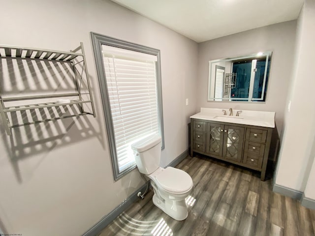 bathroom featuring toilet, vanity, baseboards, and wood finished floors