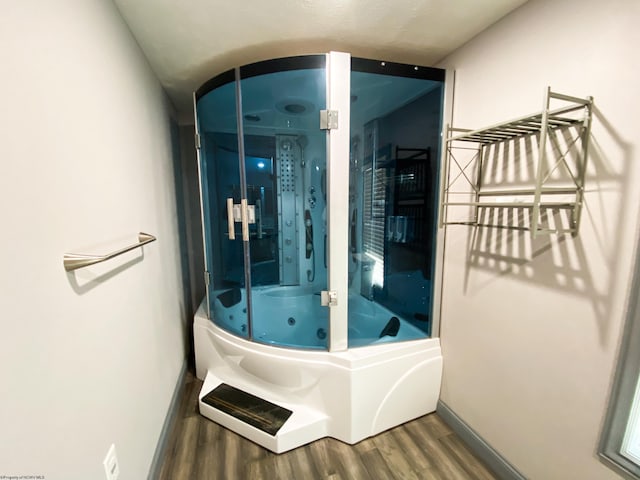full bath featuring baseboards, wood finished floors, and a whirlpool tub