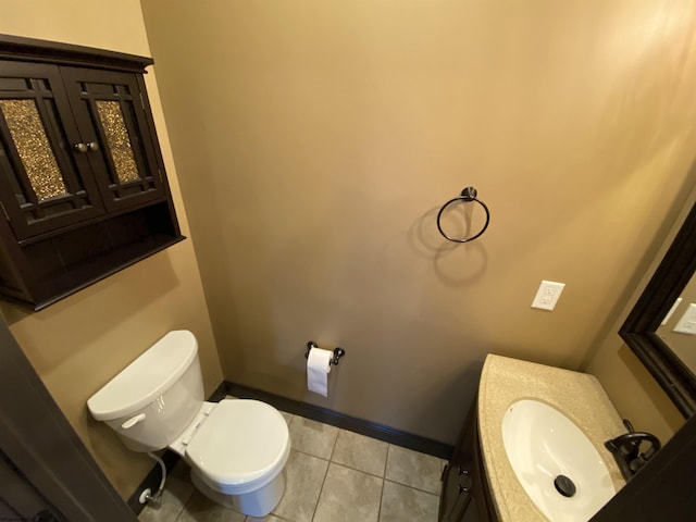 half bathroom featuring tile patterned floors, toilet, vanity, and baseboards