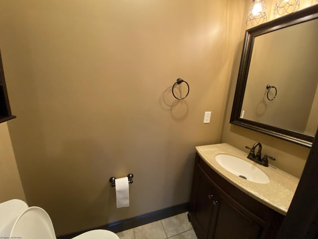 half bathroom featuring toilet, vanity, baseboards, and tile patterned flooring