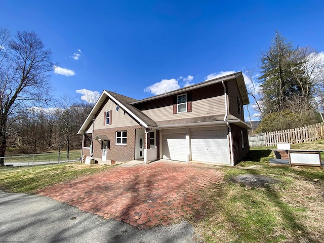 traditional-style house featuring driveway, fence, brick siding, and a garage