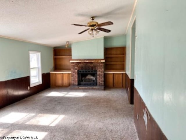 unfurnished living room with carpet flooring, a textured ceiling, a fireplace, ceiling fan, and vaulted ceiling