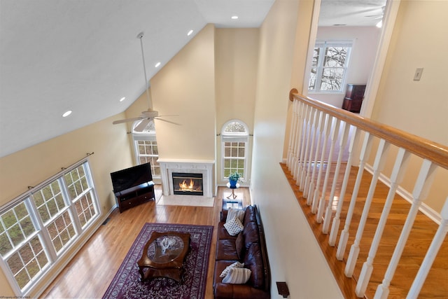 living area featuring high vaulted ceiling, a ceiling fan, a fireplace, wood finished floors, and recessed lighting