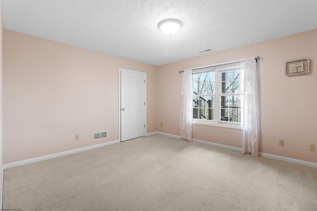 empty room with baseboards, visible vents, light colored carpet, and a textured ceiling