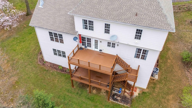 back of property featuring a shingled roof, a yard, and a wooden deck