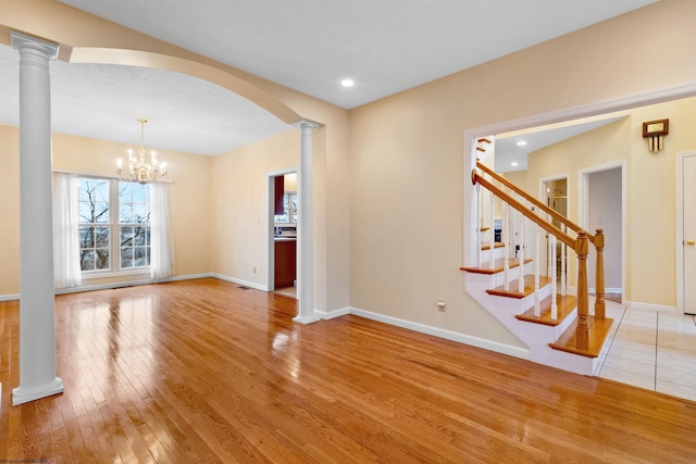 unfurnished living room with hardwood / wood-style floors, arched walkways, and baseboards