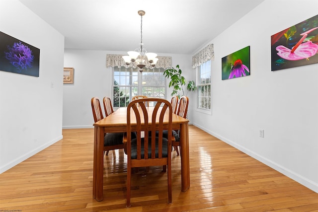dining room with light wood-style flooring, baseboards, and a chandelier