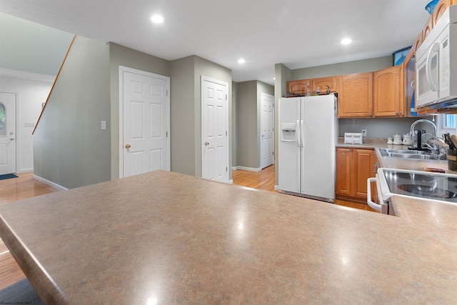 kitchen with light countertops, a sink, a peninsula, white appliances, and recessed lighting