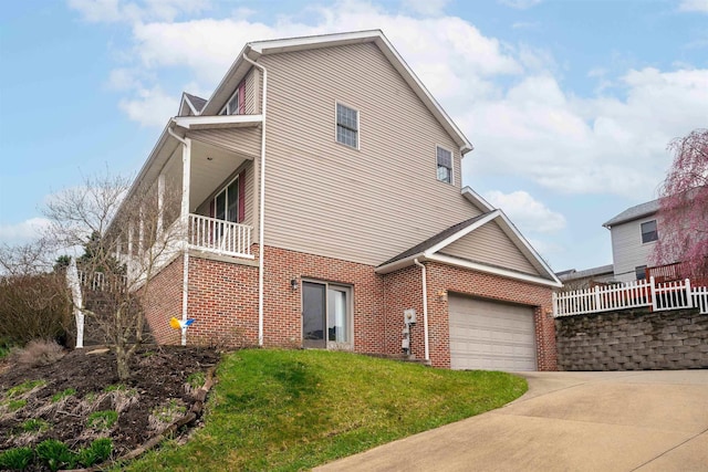 view of home's exterior featuring concrete driveway, an attached garage, brick siding, a balcony, and a lawn