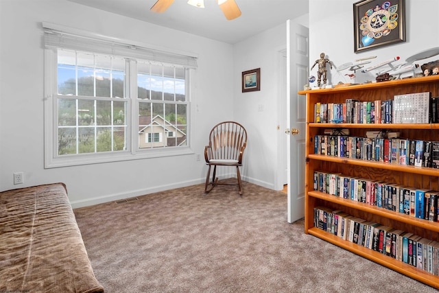 sitting room featuring baseboards, ceiling fan, and carpet