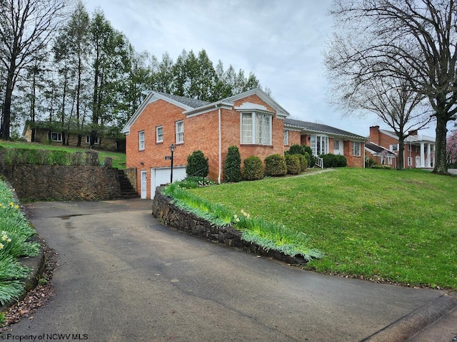 view of front of property with a front yard, driveway, brick siding, and a garage