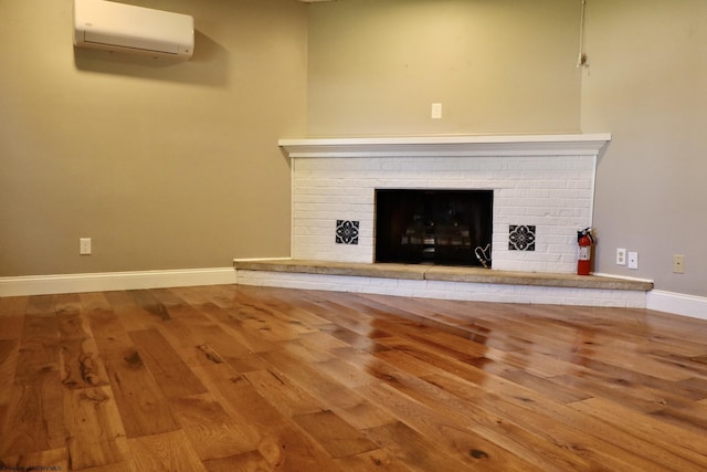 room details featuring a wall mounted AC, a fire extinguisher, a brick fireplace, baseboards, and wood finished floors