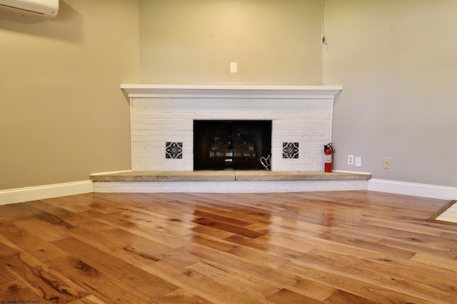 details featuring a fireplace, wood finished floors, a wall unit AC, and a fire extinguisher