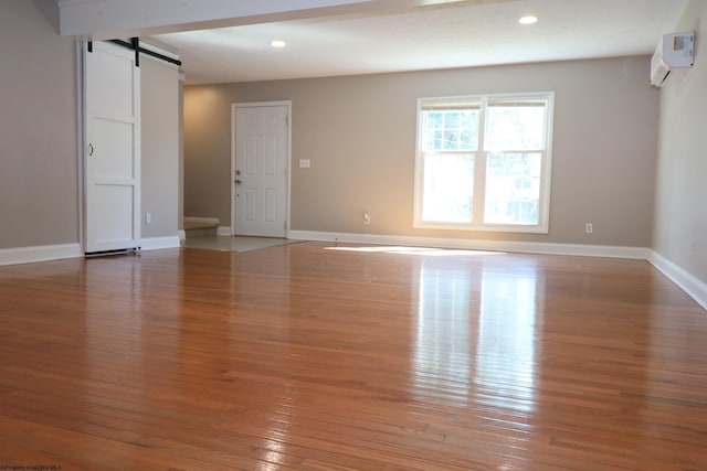 empty room featuring light wood-type flooring, a barn door, and recessed lighting