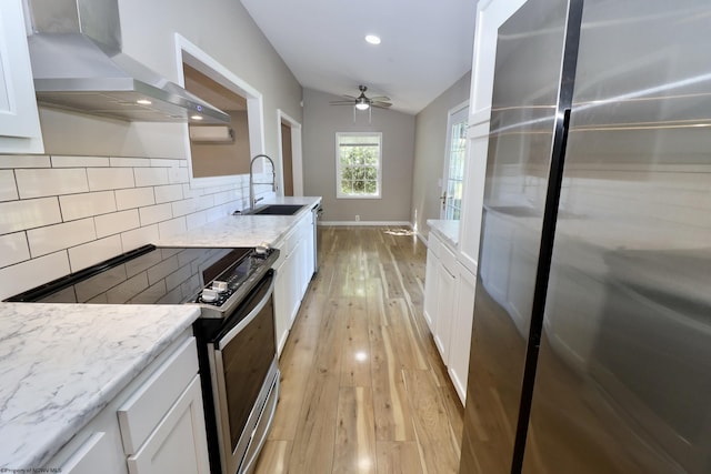 kitchen with white cabinets, wall chimney exhaust hood, electric stove, a sink, and freestanding refrigerator