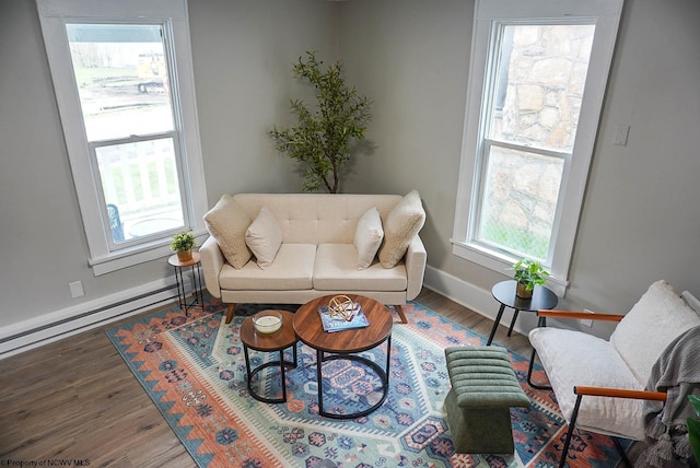 living area featuring baseboard heating, baseboards, and wood finished floors