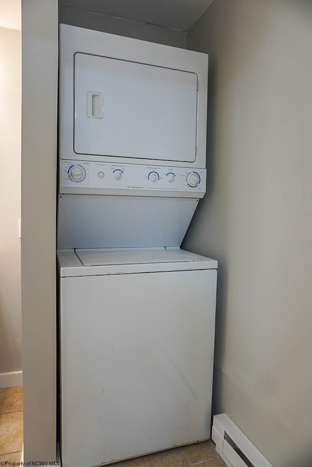 washroom featuring stacked washing maching and dryer, baseboard heating, laundry area, and baseboards