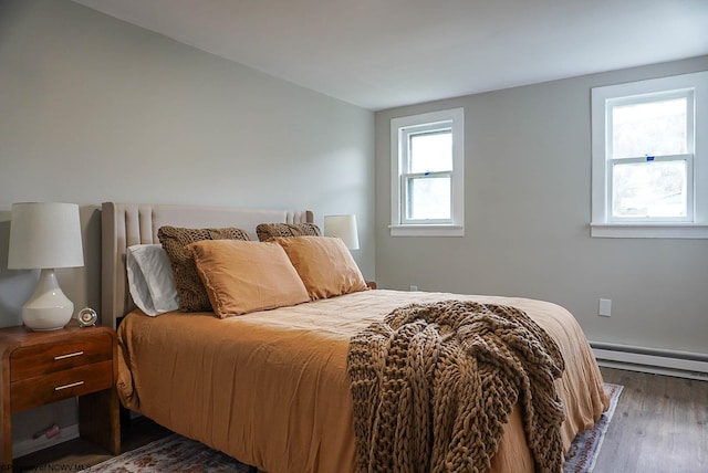 bedroom with wood finished floors and a baseboard heating unit