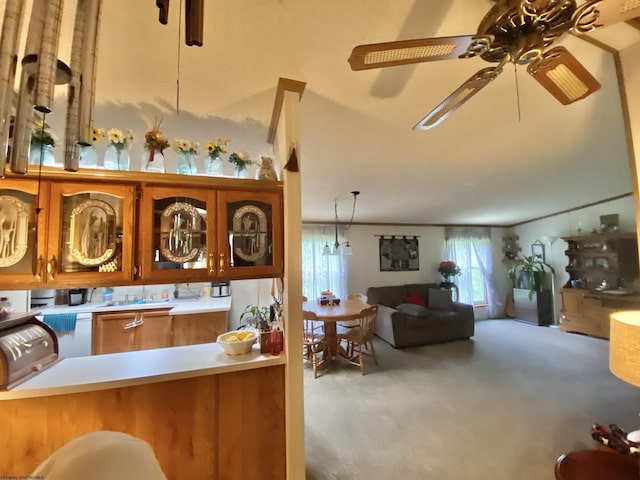 kitchen with open floor plan, light countertops, a ceiling fan, brown cabinetry, and hanging light fixtures