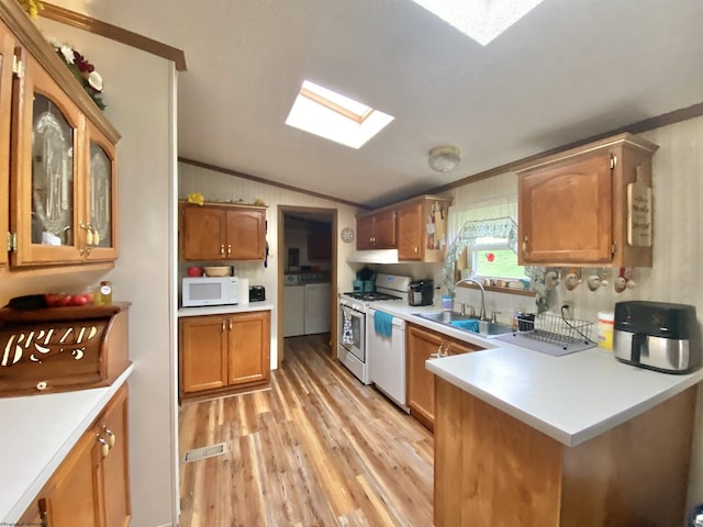 kitchen featuring separate washer and dryer, white appliances, light countertops, lofted ceiling with skylight, and a sink