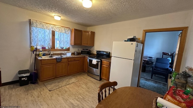 kitchen with freestanding refrigerator, electric range, light wood-style floors, brown cabinetry, and a sink