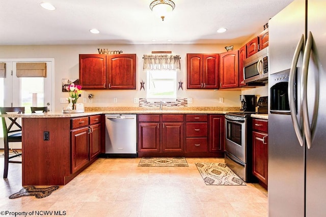 648 Ashberry Dr, Flemington, WV 26347 - kitchen with a peninsula, a sink, reddish brown cabinets, stainless steel appliances, and a breakfast bar area