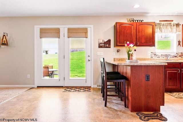 648 Ashberry Dr, Flemington, WV 26347 - kitchen featuring a peninsula, light countertops, a sink, a breakfast bar area, and baseboards