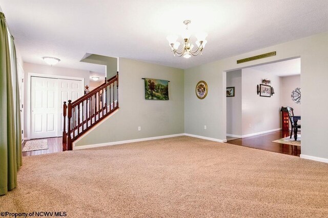 648 Ashberry Dr, Flemington, WV 26347 - carpeted empty room with baseboards, a chandelier, and stairs