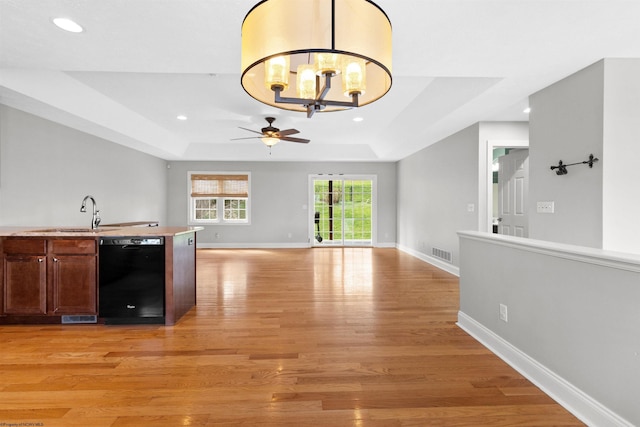 interior space with ceiling fan with notable chandelier, light wood-style flooring, visible vents, dishwasher, and a sink