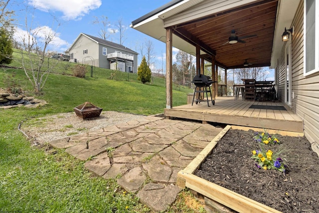 view of yard with a wooden deck, ceiling fan, a fenced backyard, an outdoor fire pit, and outdoor dining space