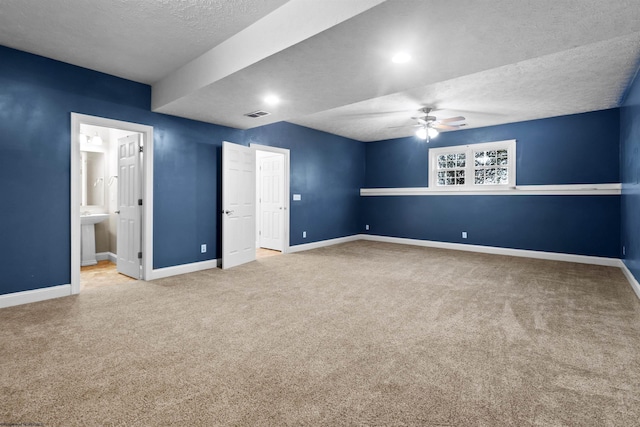 unfurnished bedroom with ensuite bathroom, carpet, a textured ceiling, visible vents, and baseboards