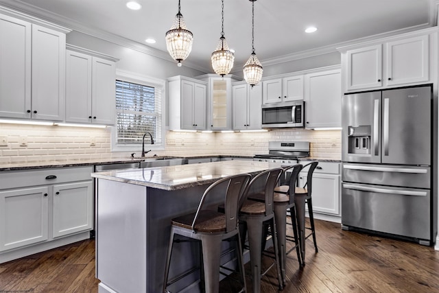kitchen with ornamental molding, recessed lighting, light stone counters, a sink, and stainless steel appliances