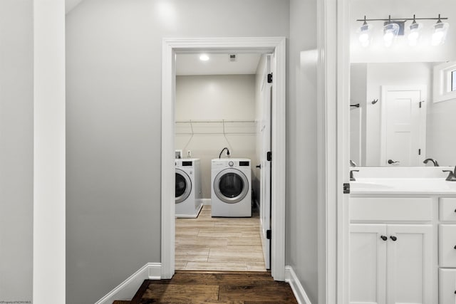 laundry room with laundry area, dark wood-type flooring, separate washer and dryer, a sink, and baseboards